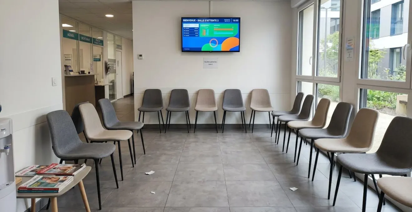 Vue grand angle d'une salle d'attente médicale contemporaine vide, avec des fauteuils design et une décoration épurée dans des tons clairs, éclairage naturel abondant